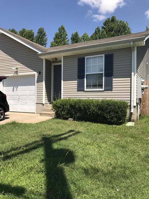 A house with a white garage door and a grey house with a brown roof.