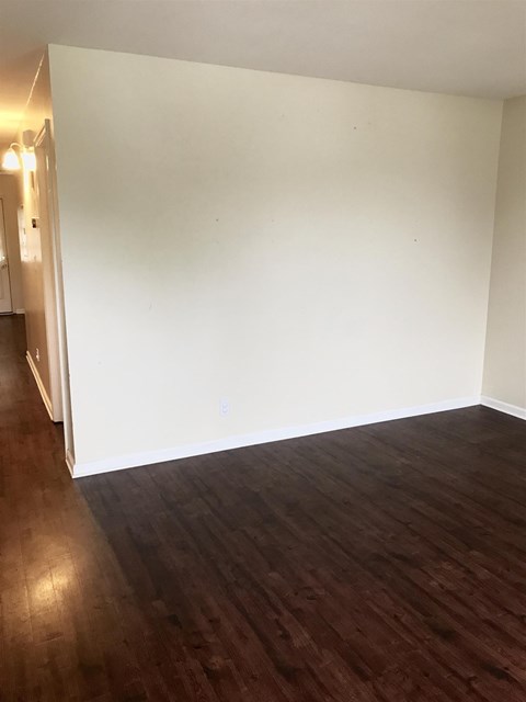 A room with wooden flooring and white walls.