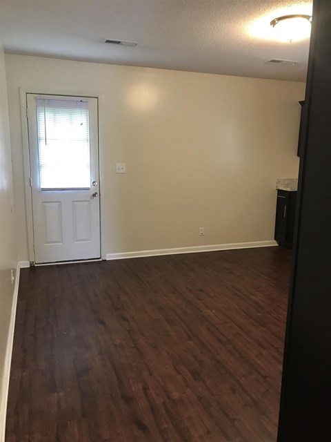 A room with a white door and wooden flooring.