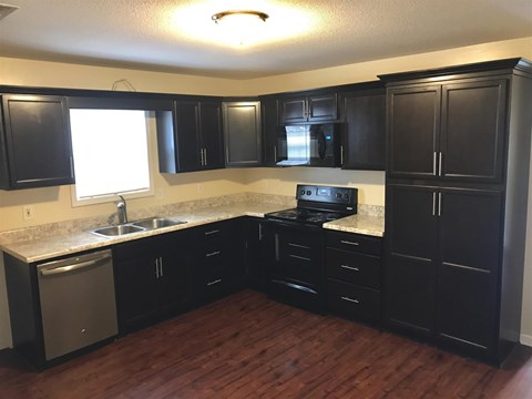 A kitchen with black cabinets and a white sink.