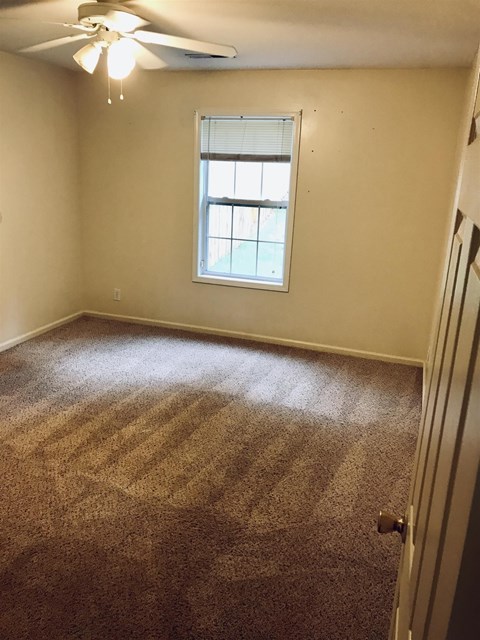 A room with a carpeted floor and a window.