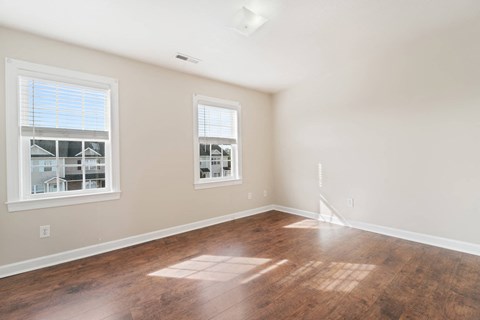 a living room with a hard wood floor and two windows