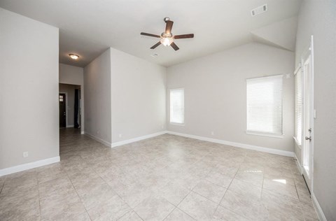 an empty living room with a ceiling fan