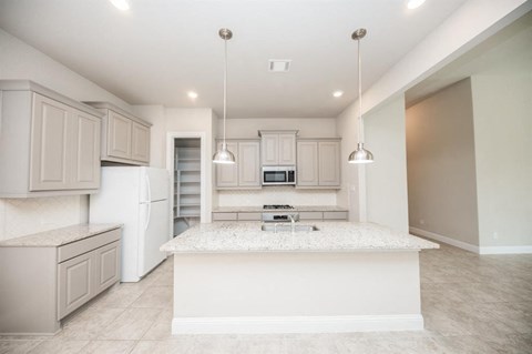 an open kitchen with white cabinets and a marble counter top