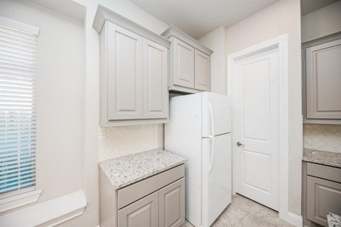 a kitchen with white cabinets and a white refrigerator