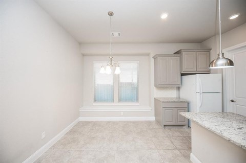 an empty kitchen with white cabinets and a window