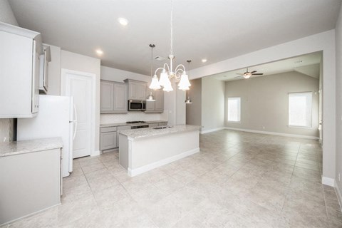an empty kitchen and living room with a refrigerator and a sink