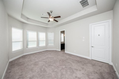 an empty living room with a ceiling fan and windows