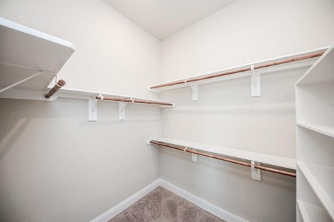 a walk in closet with white walls and shelves