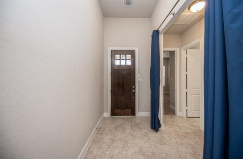 a hallway with a door to a bathroom and a blue curtain
