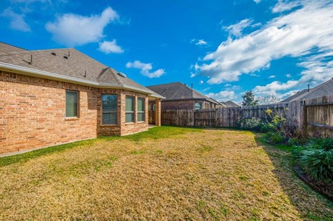 a backyard with a brick house and a wooden fence
