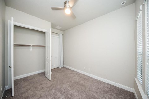an empty bedroom with a closet and a ceiling fan