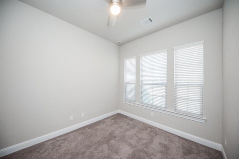 an empty room with three windows and carpet