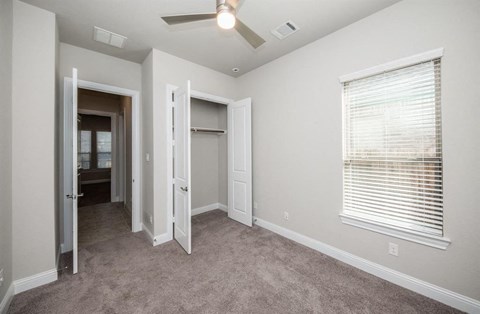 a carpeted room with a large window and a ceiling fan