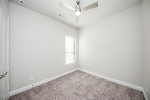 an empty room with a ceiling fan and a window