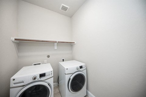 a white laundry room with two washes and a dryer