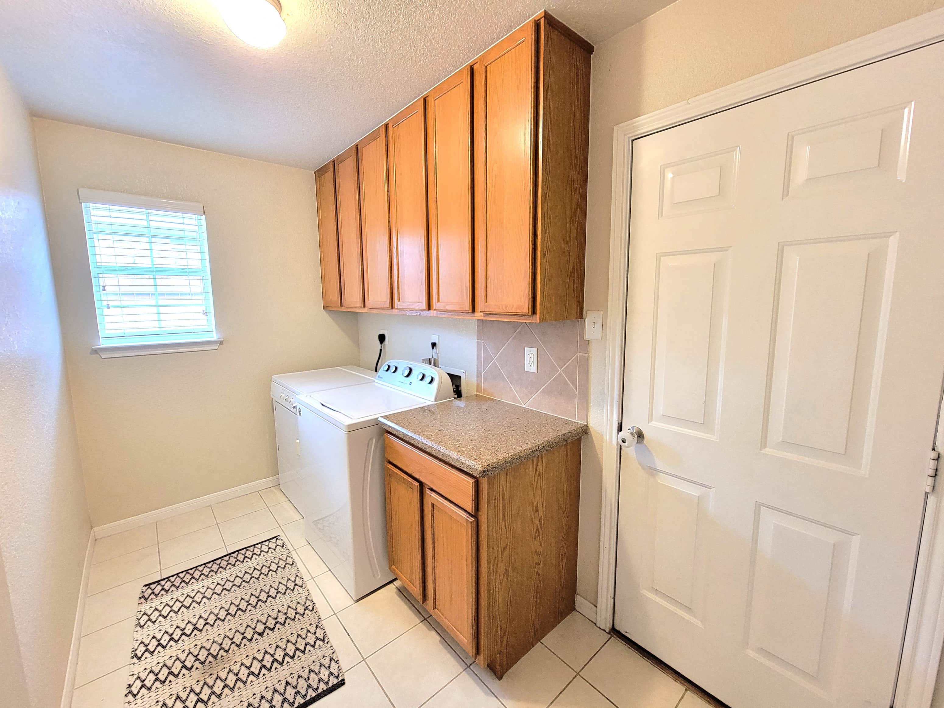 a small laundry room with a washer and dryer and wooden cabinets