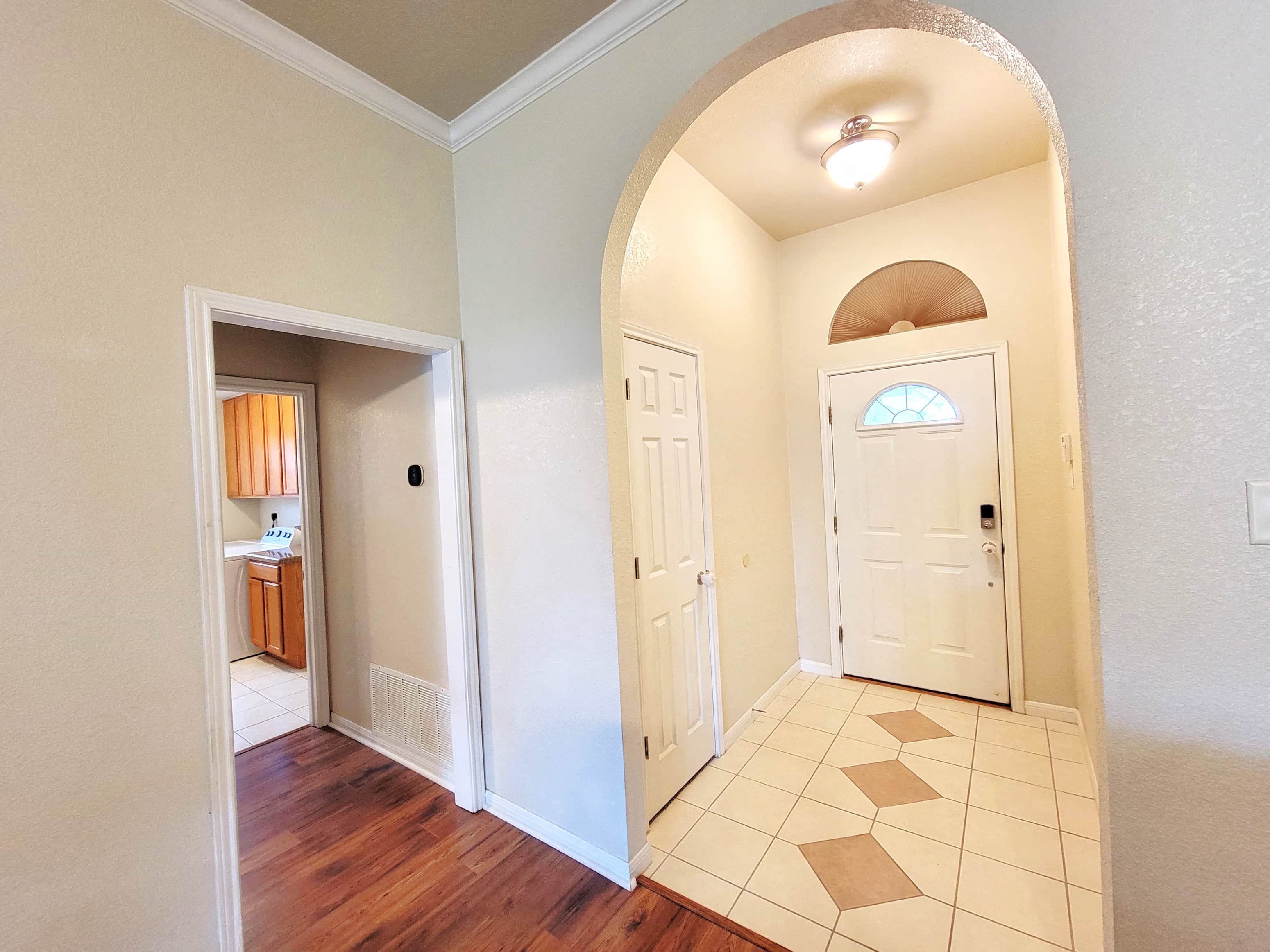 a entryway with a white door and a hallway with a door to a bathroom