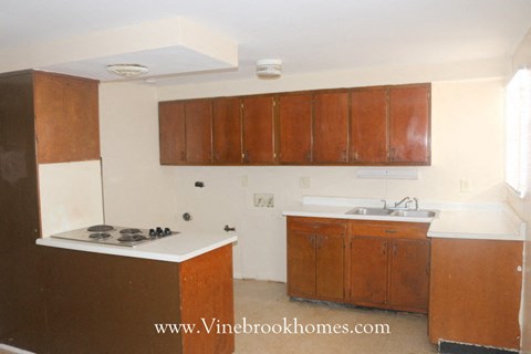 A kitchen with brown cabinets and a white stove top oven.