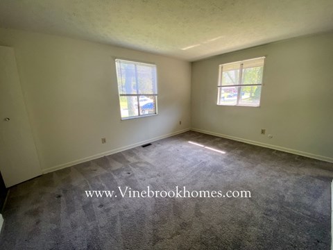 the living room of a home with carpet and two windows