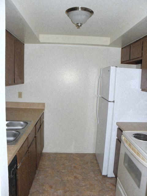 A kitchen with brown cabinets and a white refrigerator.
