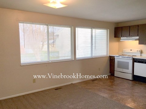 A kitchen area with a white stove and a window with blinds.