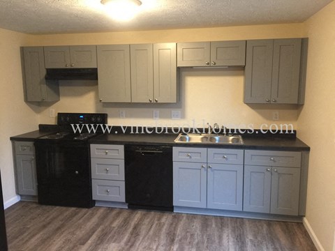 a kitchen with white cabinets and black counter tops