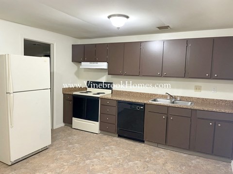 A kitchen with brown cabinets and a white fridge.