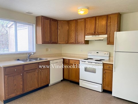 A kitchen with white appliances and wooden cabinets.