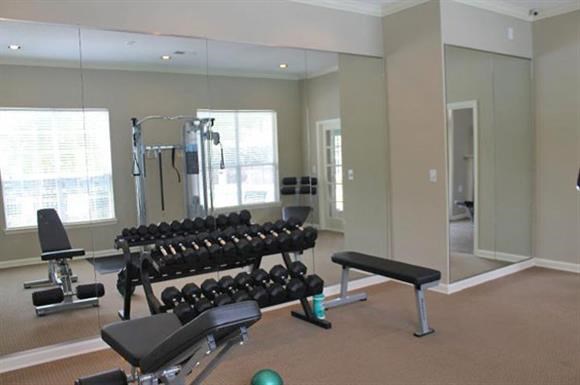 a fitness room with some weights and a mirror