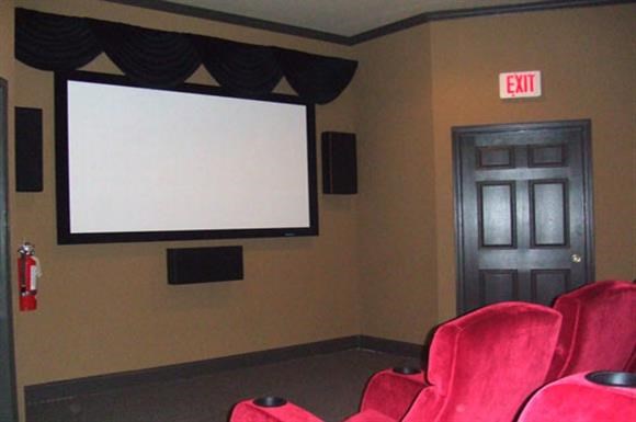 a theater room with red chairs and a projector screen