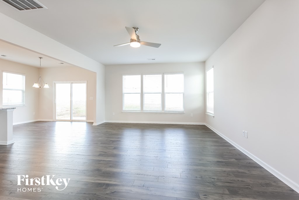an empty living room with white walls and a ceiling fan