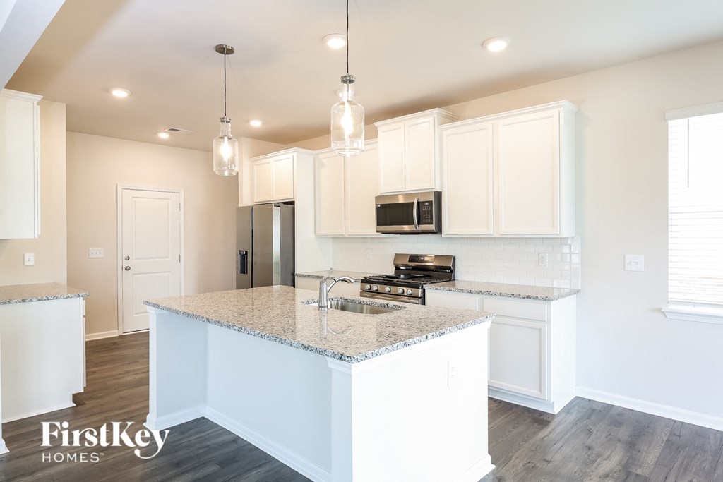 a kitchen with white cabinets and a marble counter top