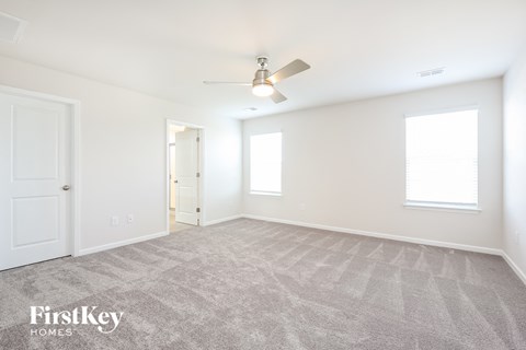 a spacious living room with carpet and a ceiling fan