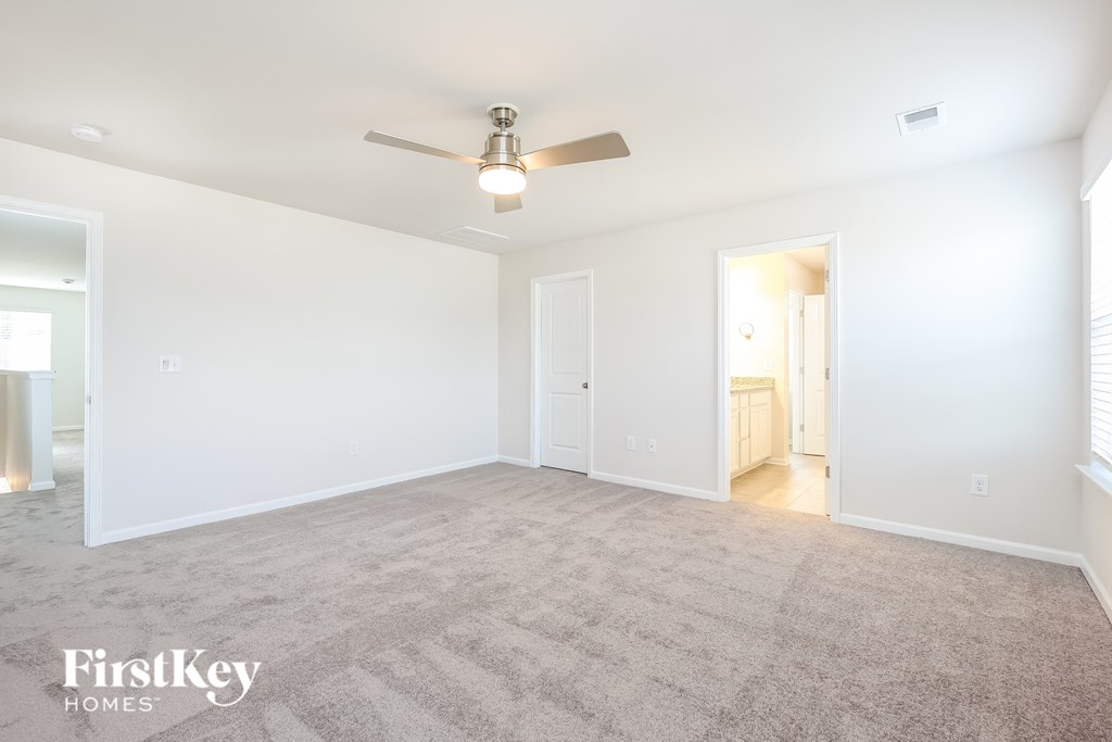 an empty living room with a ceiling fan and white walls