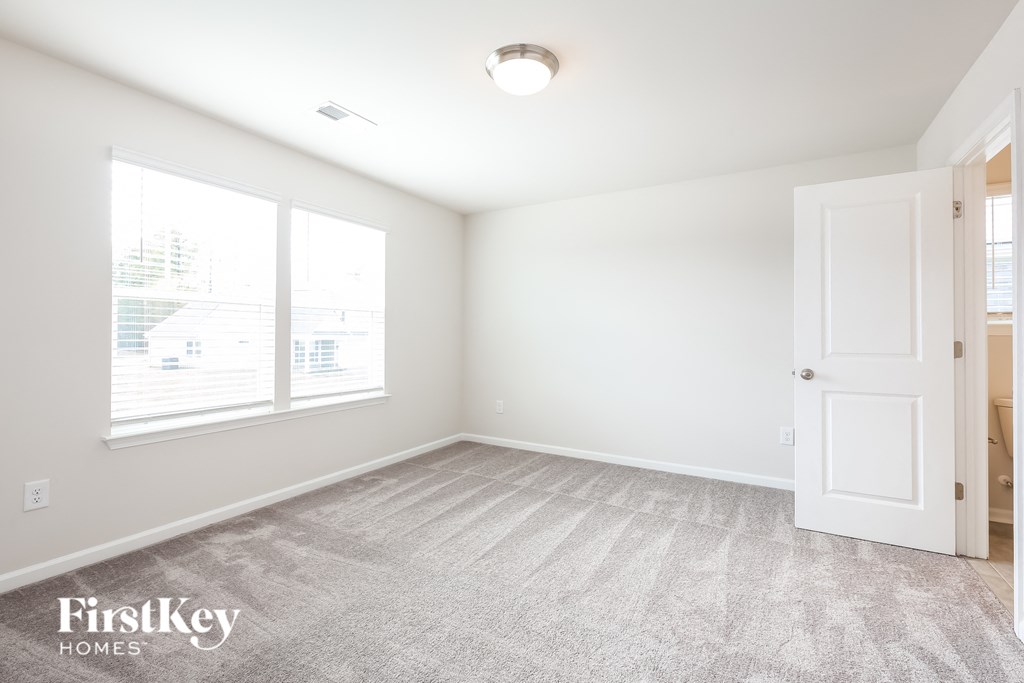 an empty room with a door and two windows