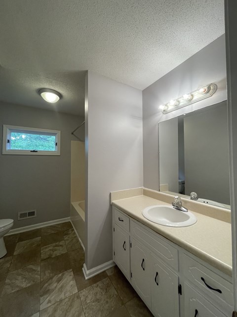 A bathroom with a sink, mirror, and tiled floor.