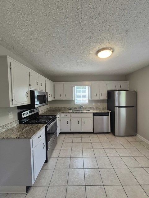 A kitchen with white cabinets and a granite counter top.