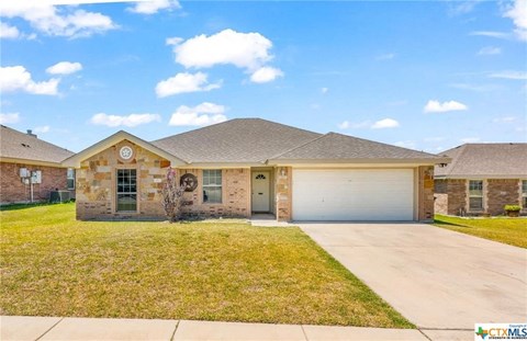 a brick house with a garage and a lawn
