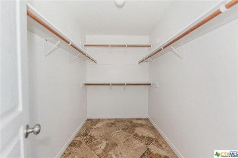 a walk in closet with white walls and shelves