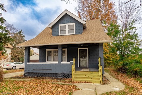 a blue house with a brown roof and a porch