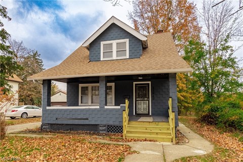 a blue house with a brown roof and a porch