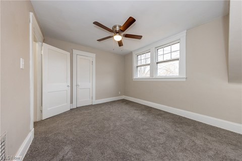 an empty living room with a ceiling fan and a window