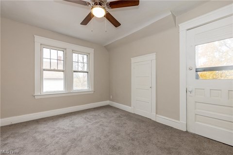 an empty bedroom with a ceiling fan and two windows