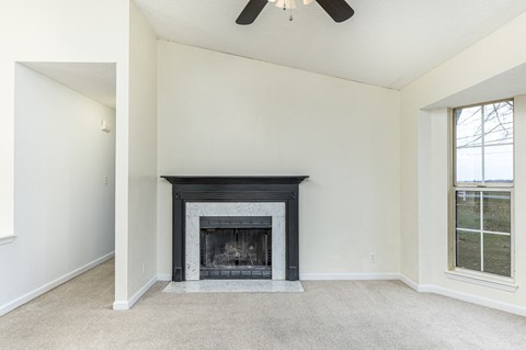 A living room with a fireplace and a ceiling fan.
