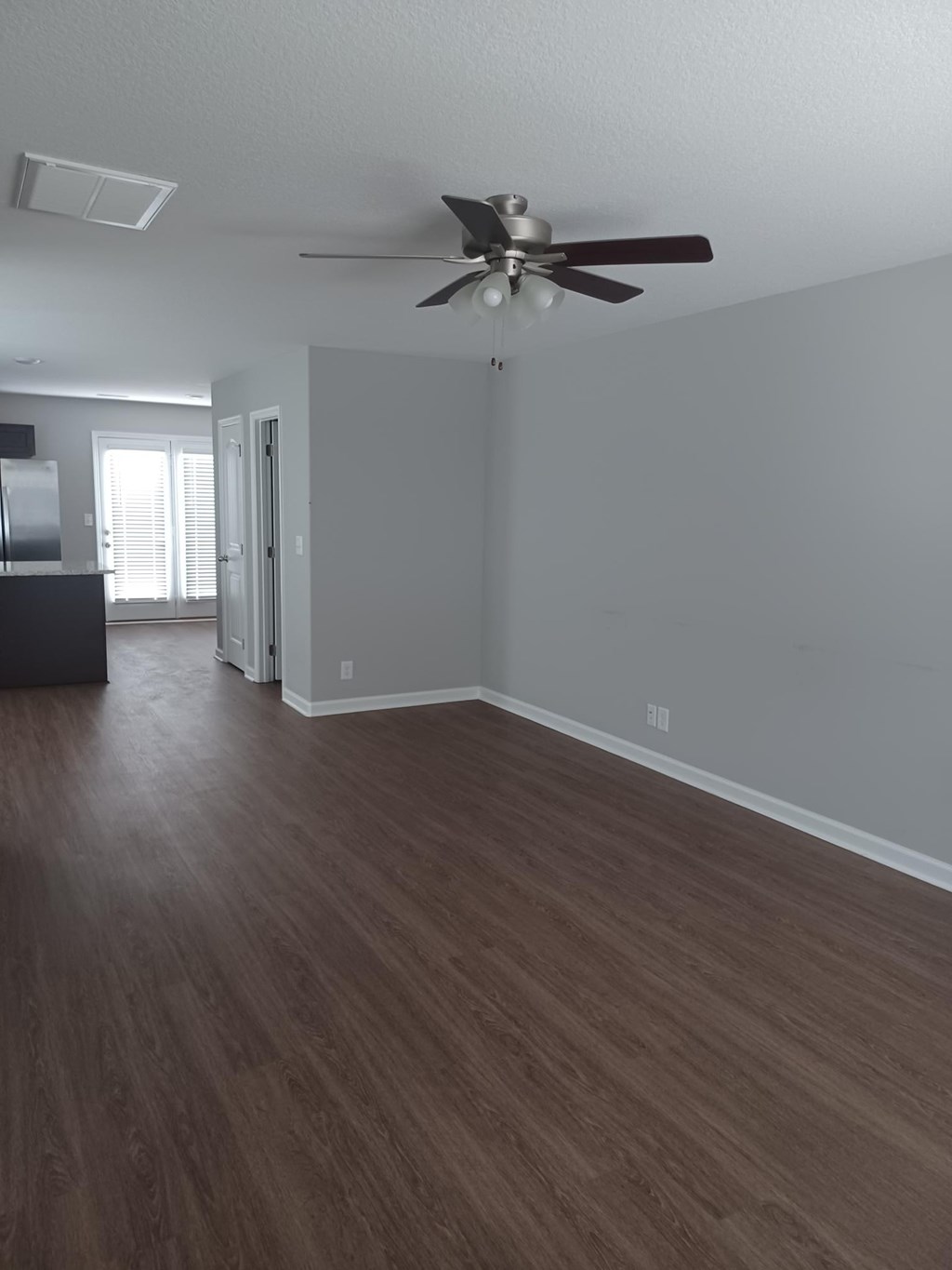 A room with a ceiling fan and wood flooring.