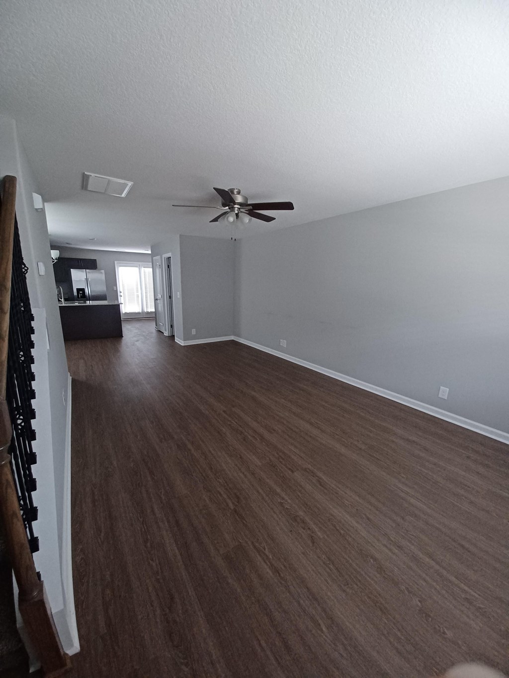 A room with a ceiling fan and wooden flooring.