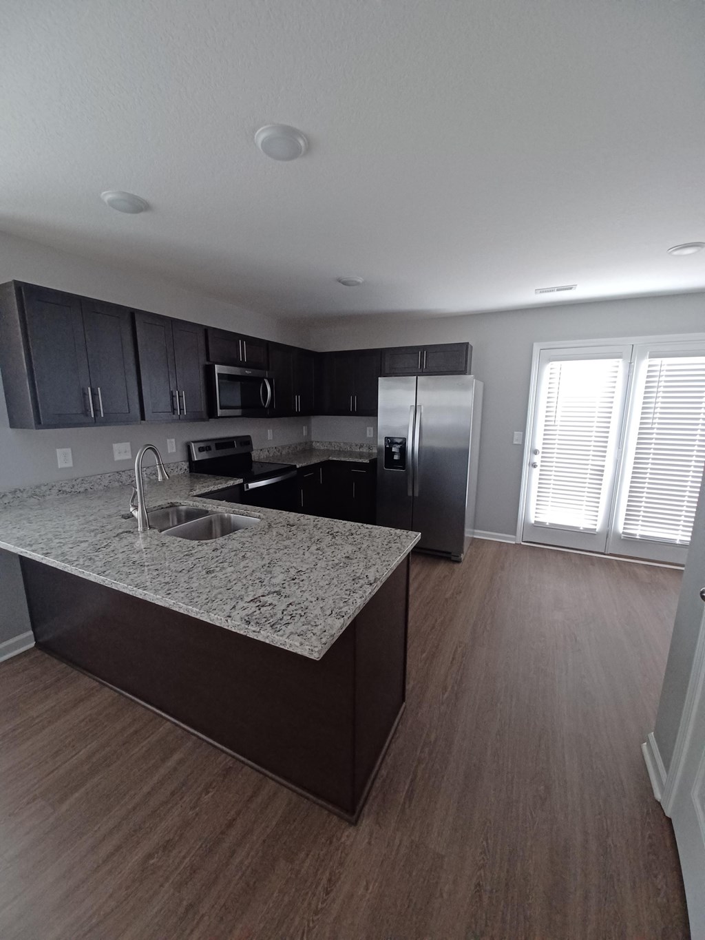 A kitchen with a granite countertop and wooden flooring.
