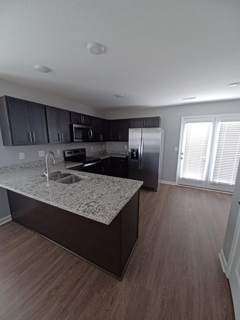 A kitchen with a granite countertop and wooden flooring.