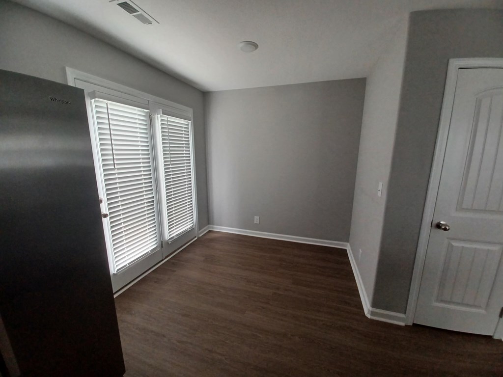 A room with a door and a window with blinds.